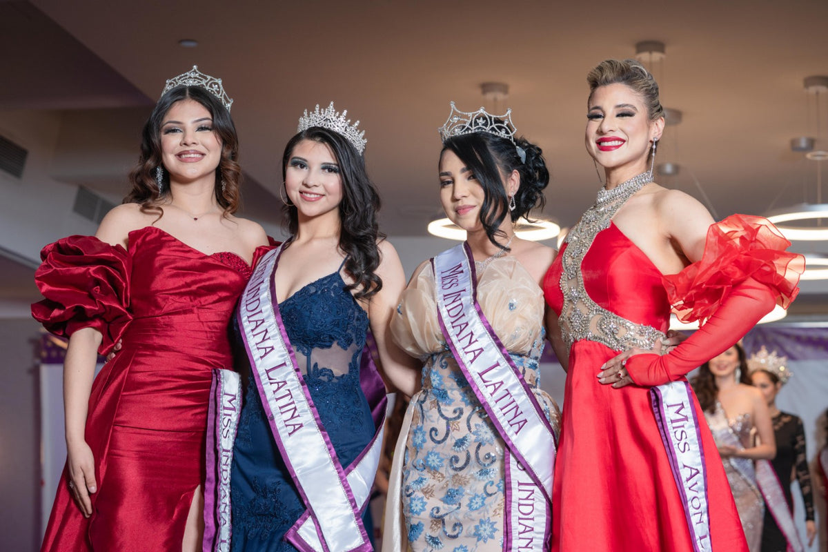 Four pageant titleholders posing together in evening gowns and sashes